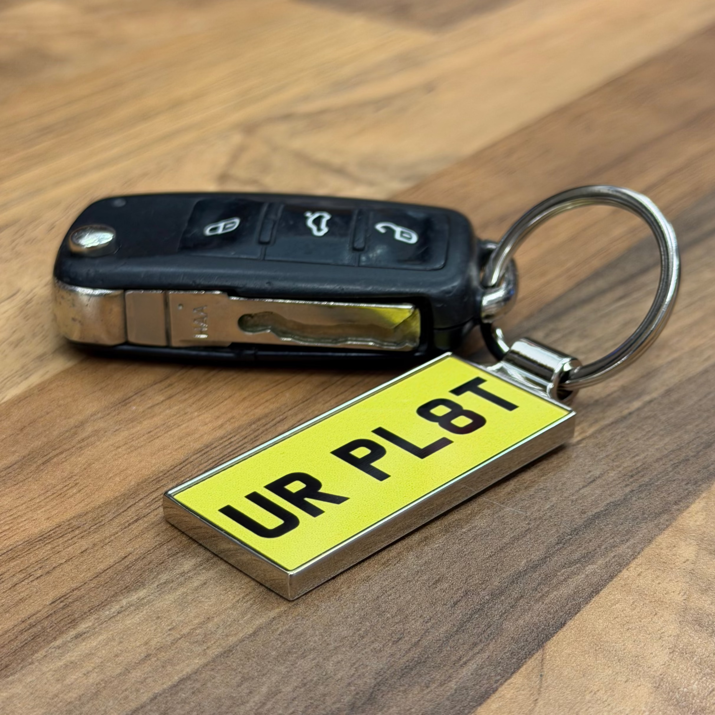 Keychain with a yellow license plate holder on a wooden surface